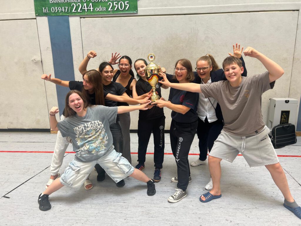 Eine Gruppe Mädels und ein Junge halten den Pokal hoch und freuen sich