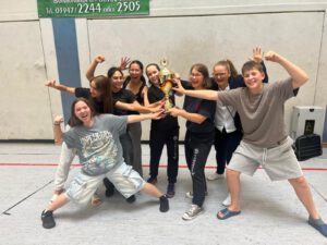 Eine Gruppe Mädels und ein Junge halten den Pokal hoch und freuen sich