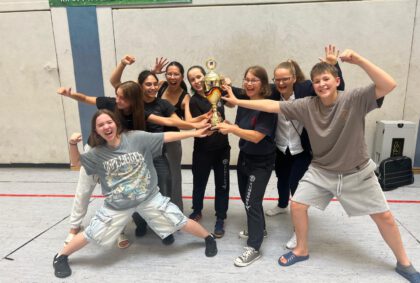 Eine Gruppe Mädels und ein Junge halten den Pokal hoch und freuen sich