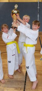 3 Kinder halten den Pokal in die Höhe