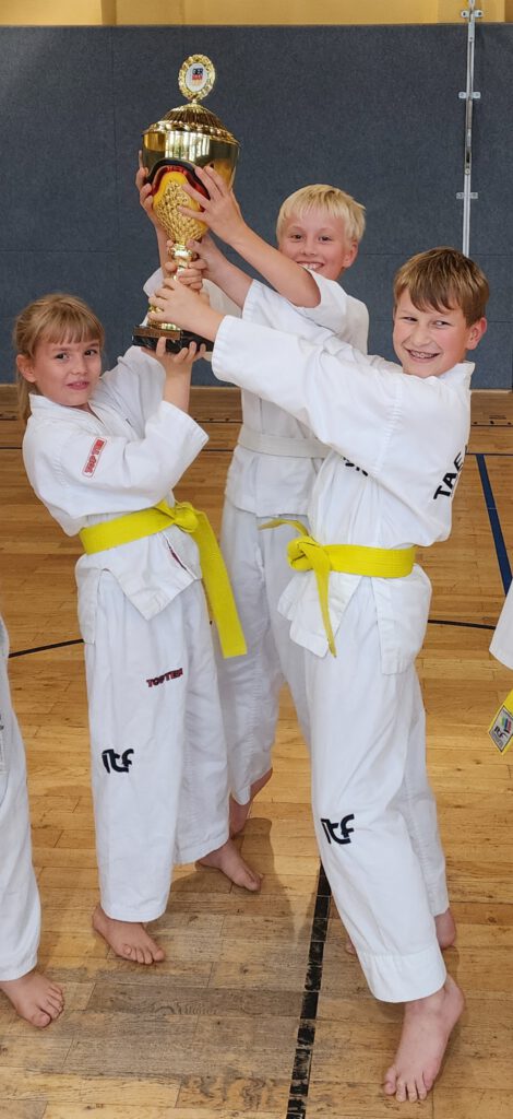 3 Kinder halten den Pokal in die Höhe